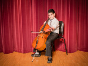 Young boy with limb difference playing cello adaptively
